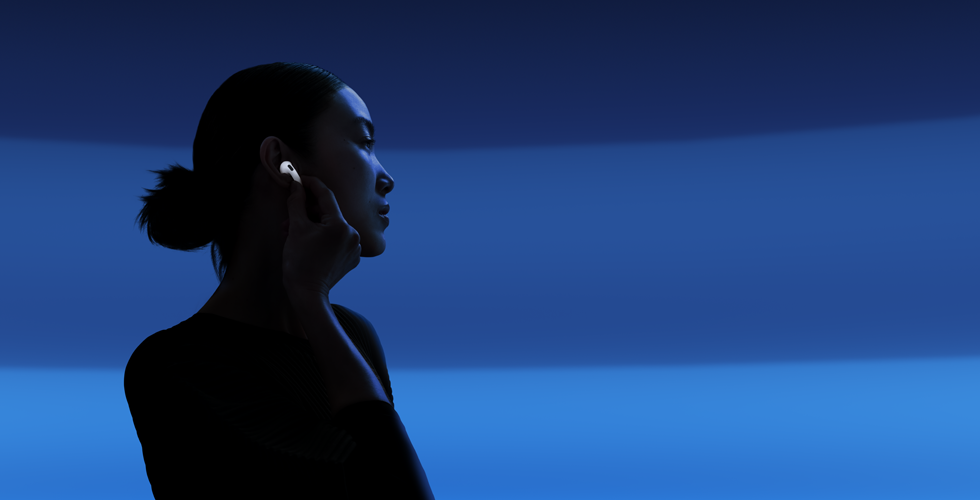 Žmogus nykščiu ir smiliumi laiko savo „AirPods 5“ kojelę, kad pakeistų klausymosi režimus