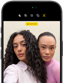 „iPhone 18 Pro“, juoda spalva, priekinė pusė iš išorės, ekrane du modeliai pozuoja kamerai – demonstruojama „Center Stage“ priekinė kamera