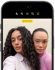 „iPhone 18 Pro“, juoda spalva, priekinė pusė iš išorės, ekrane du modeliai pozuoja kamerai – demonstruojama „Center Stage“ priekinė kamera