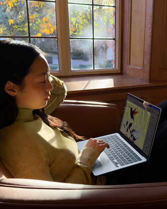 A person sitting in a chair using their „MacBook Air“